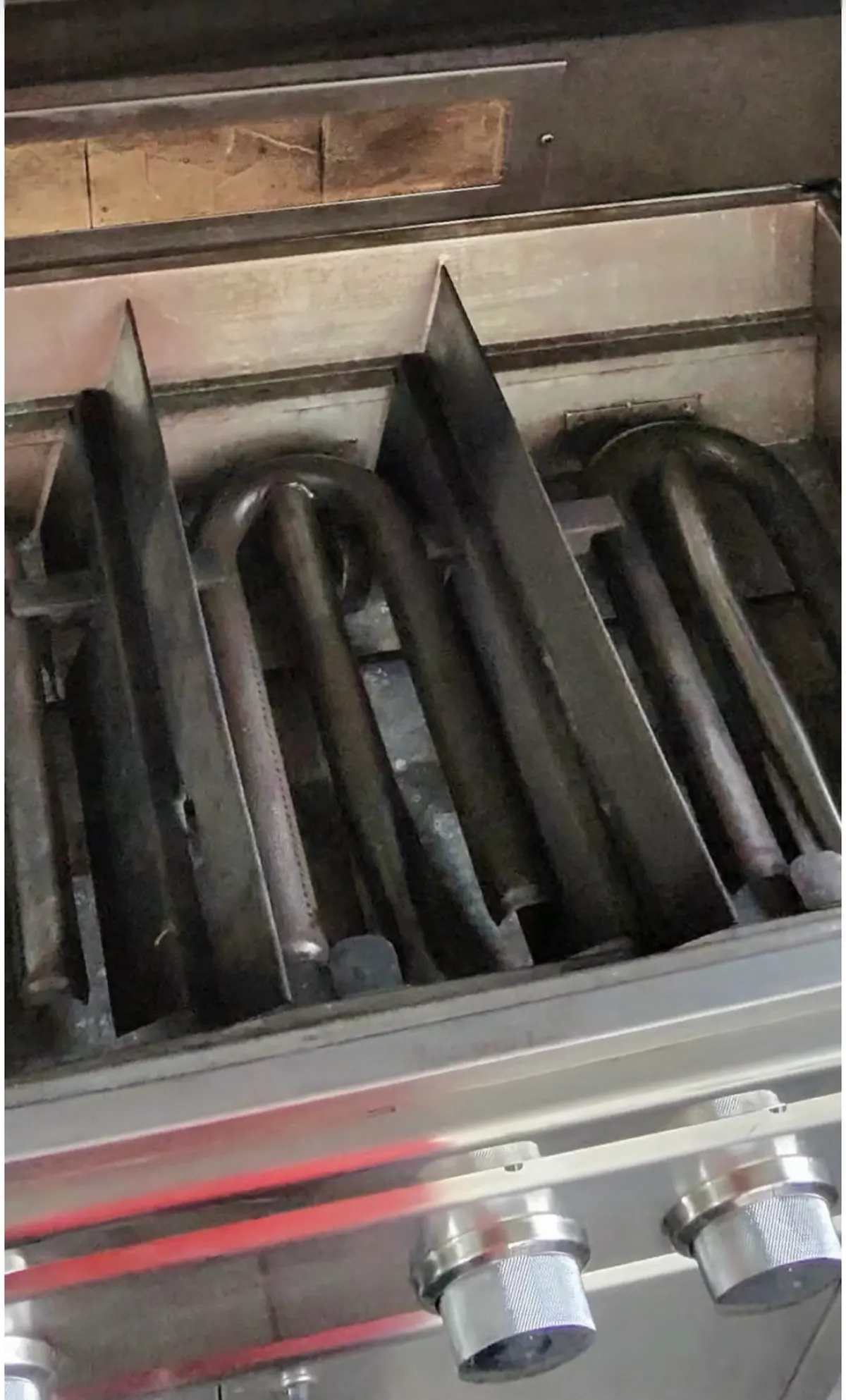 The same grill's burner tubes reinstalled and cleaned back to bare stainless steel after restoration