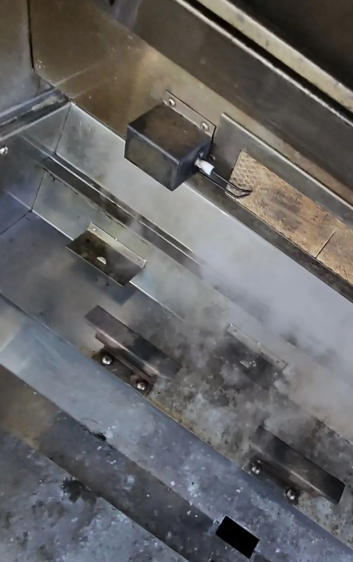 The same grill's lower housing cleaned to clean stainless steel with the igniter box and brackets visible